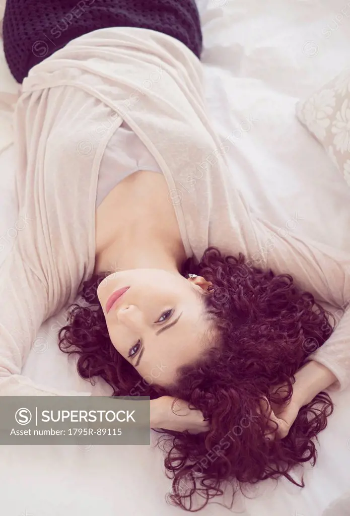 Portrait of beautiful brunette woman lying on bed