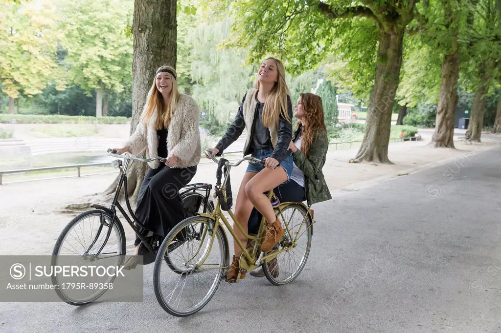Female friends riding bike in park