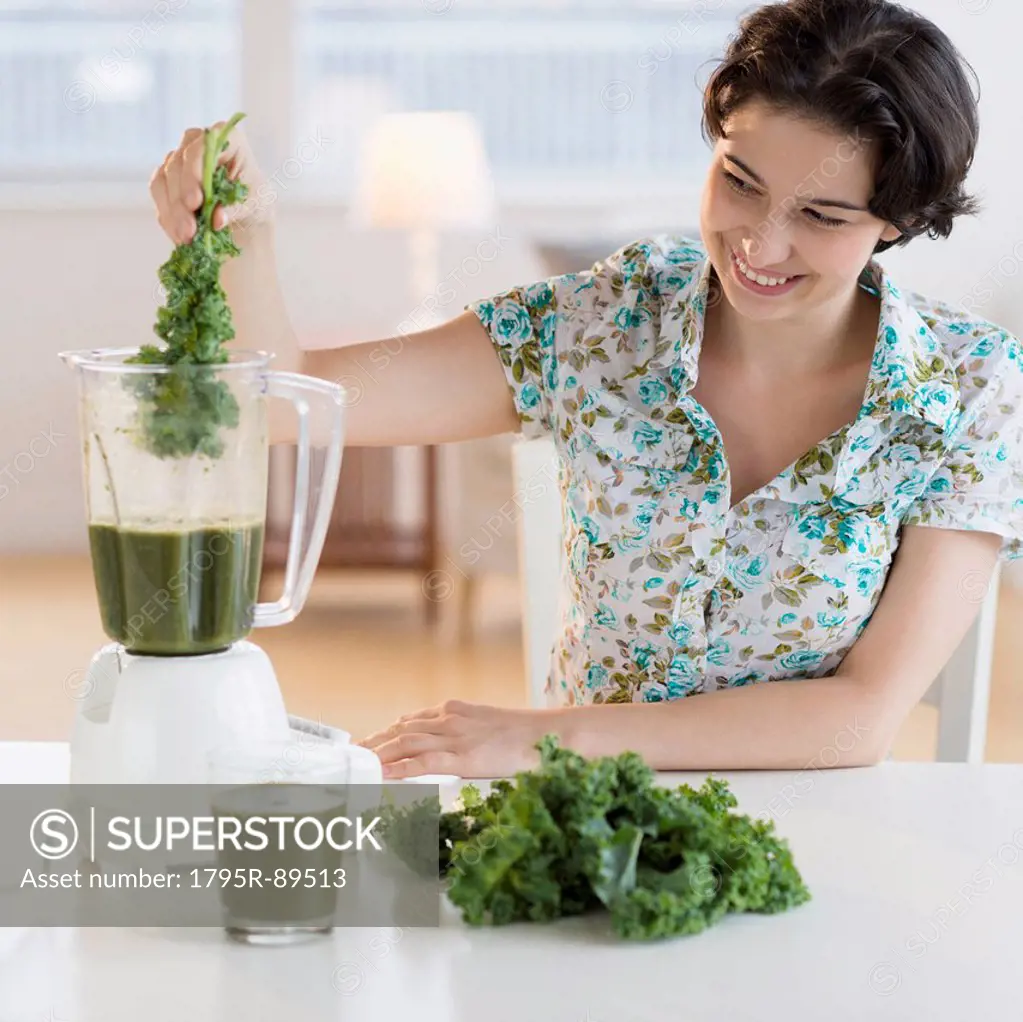 Woman preparing healthy drink with kale