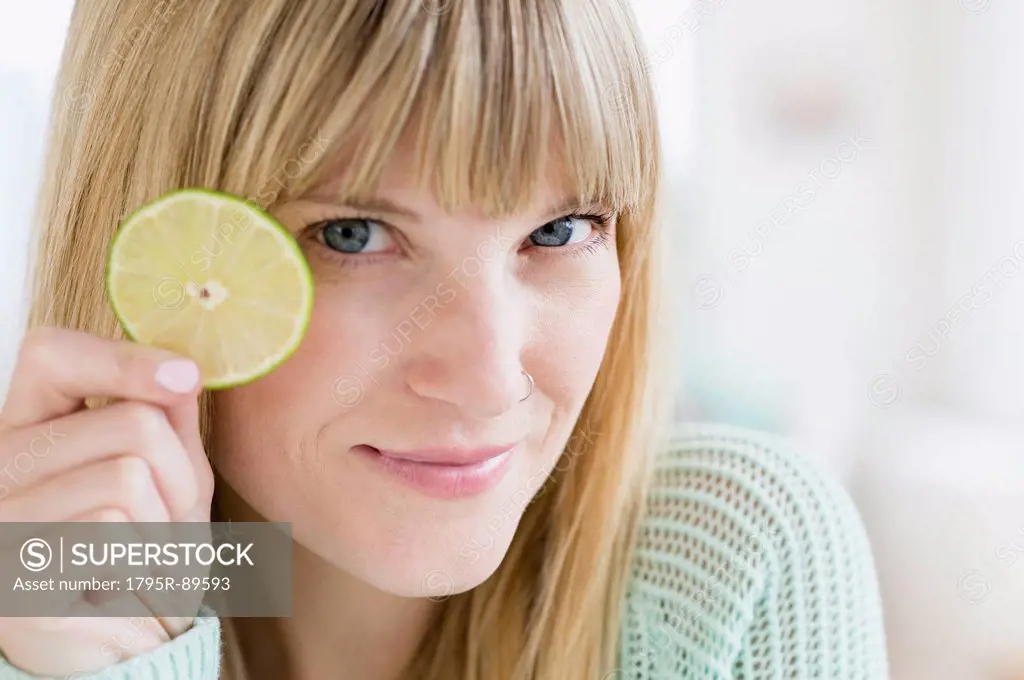 Portrait of woman holding slice of lime