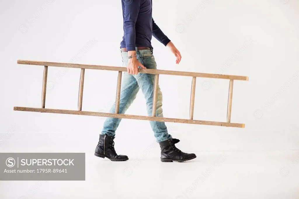 Low section of man carrying ladder