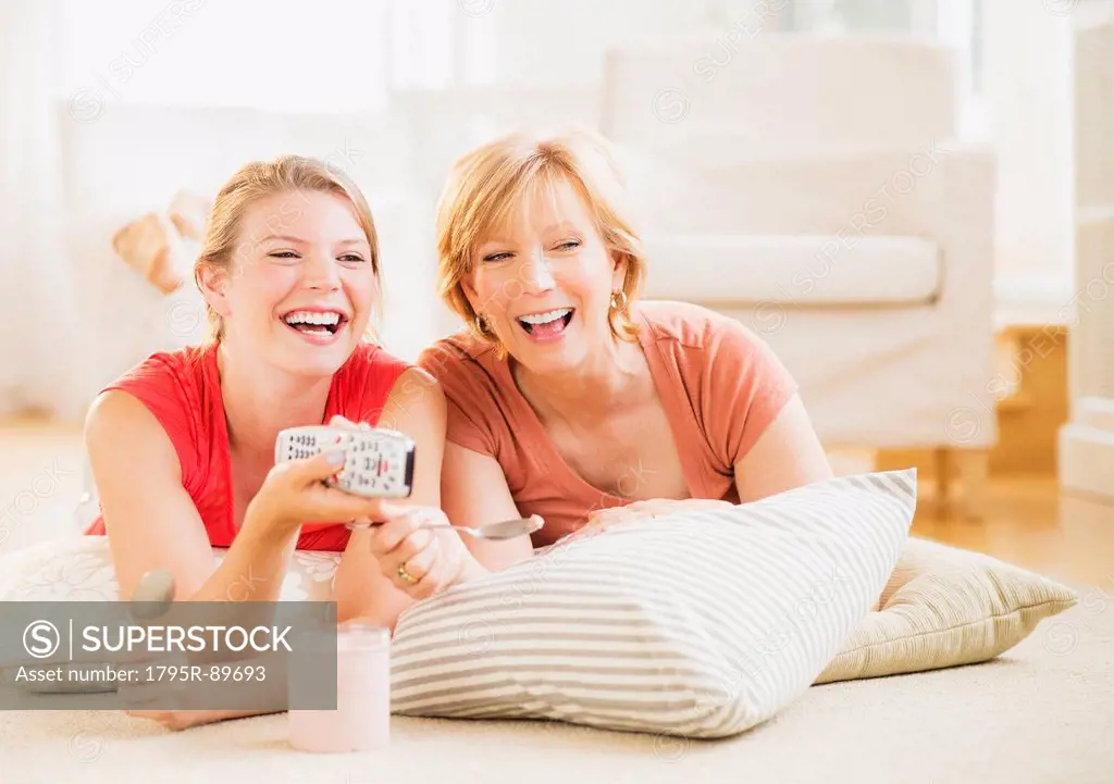 Mother and adult daughter relaxing at home, watching tv