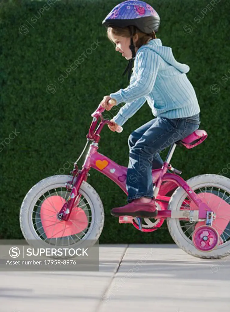 Girl riding bicycle with training wheels