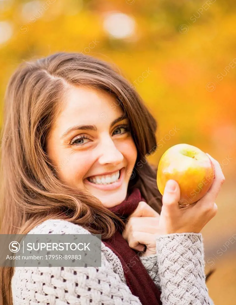 Portrait of young woman in Central Park holding apple