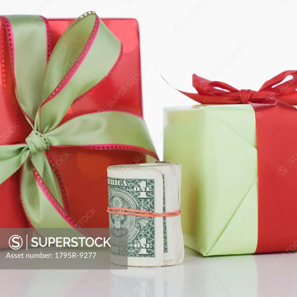 Studio shot of roll of dollar bills and gifts