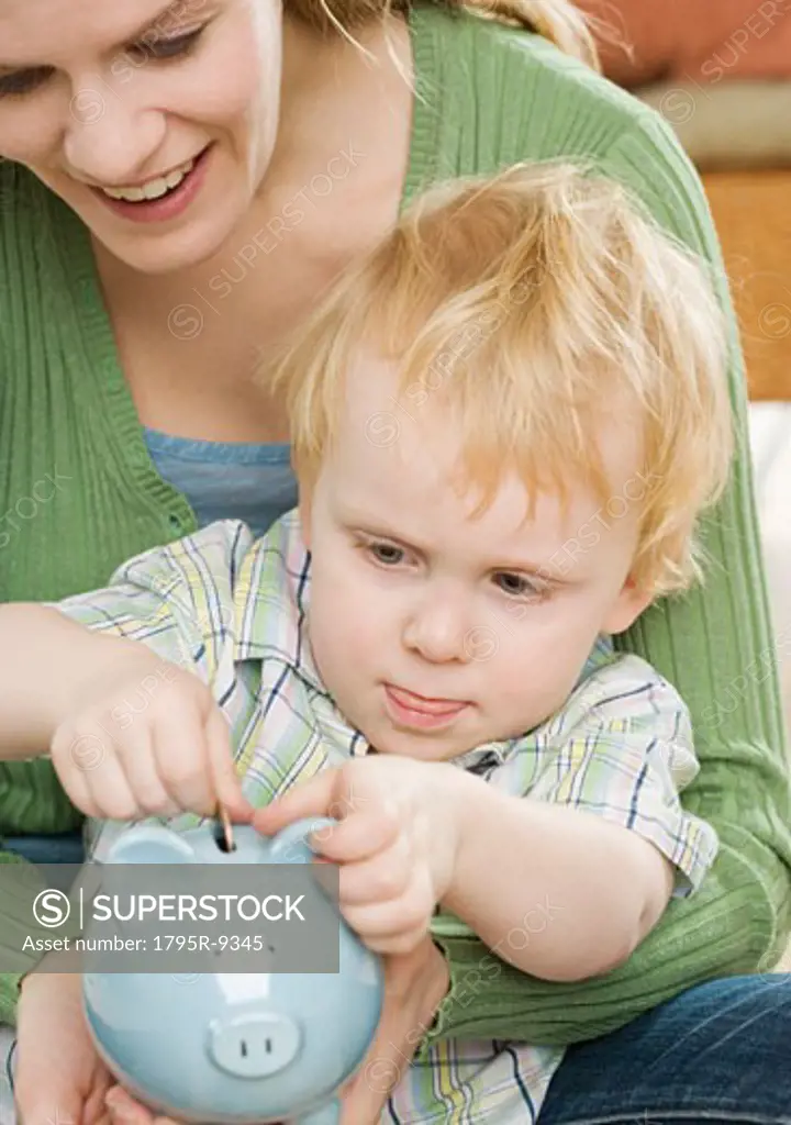 Mother and young son putting change in piggy bank