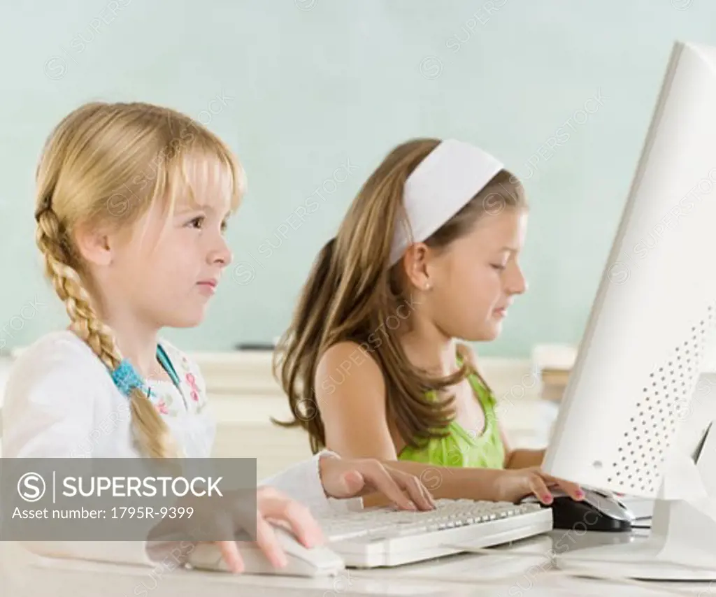 Two young girls using computers