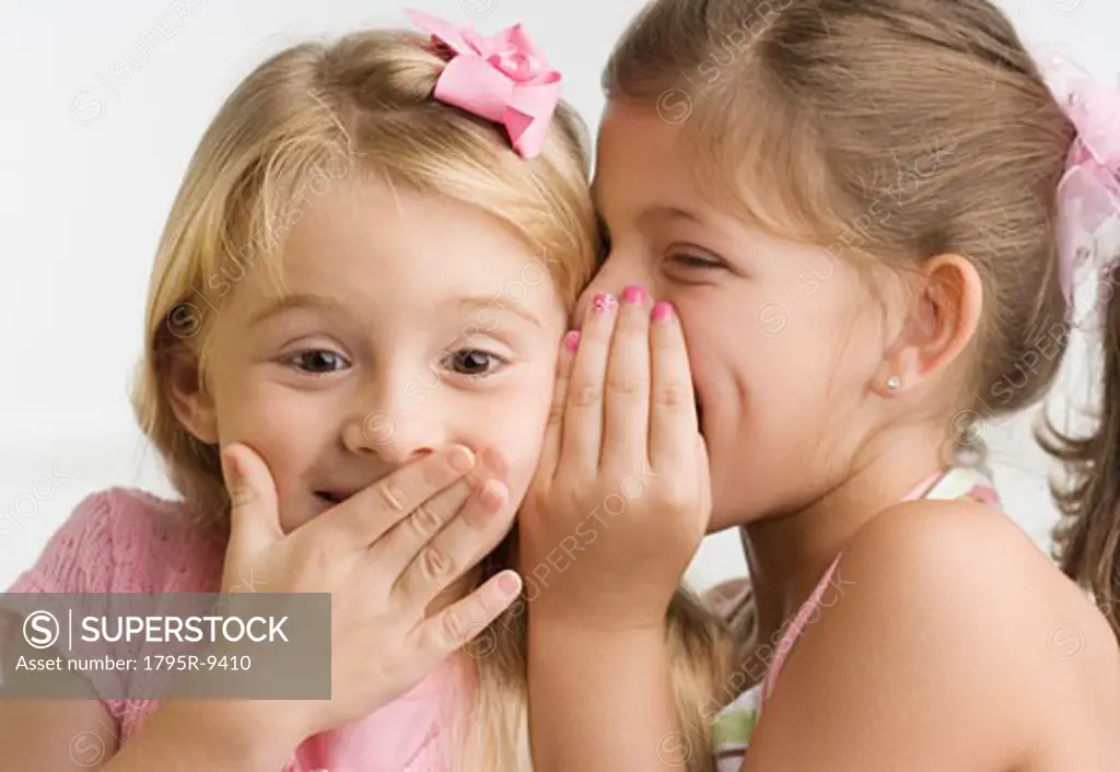 Young girl telling sister a secret