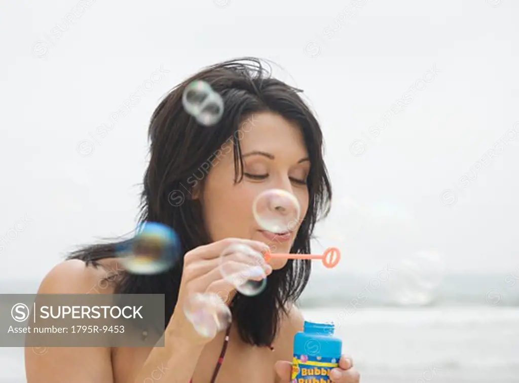 Woman blowing bubbles at beach