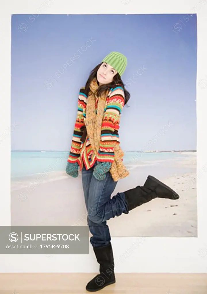 Woman in winter clothing in front of beach picture