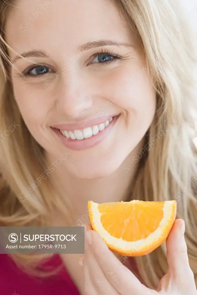 Close-up of woman holding orange wedge