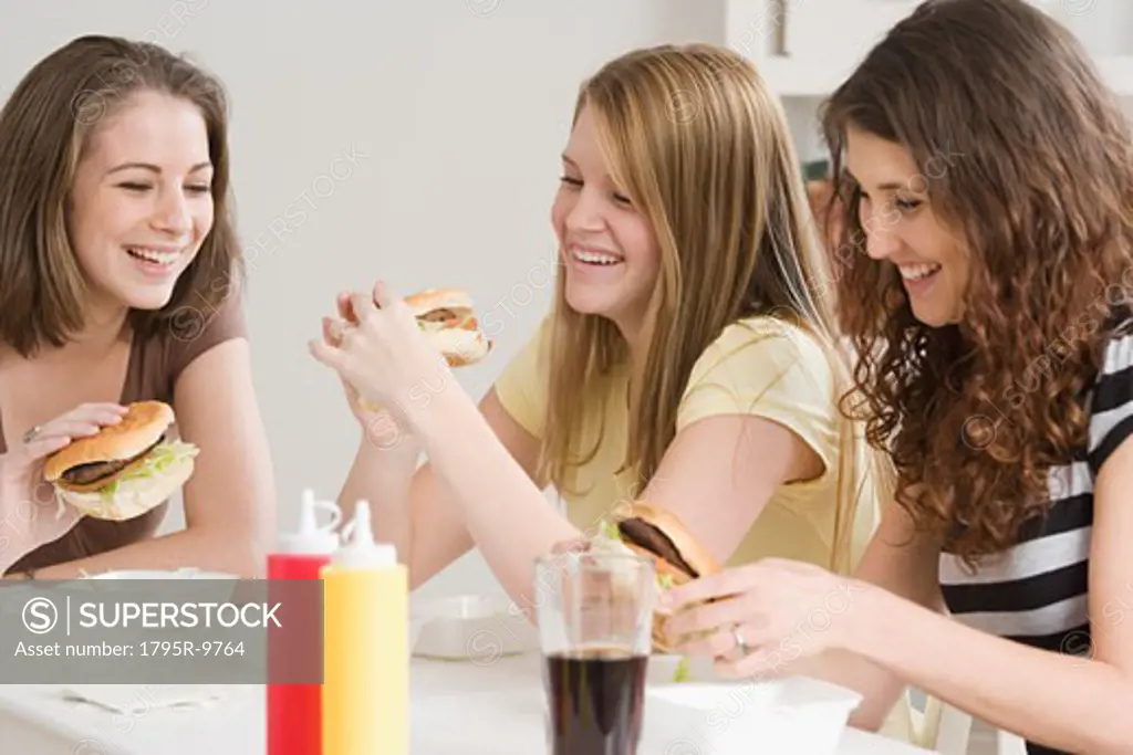 Teenage girls eating hamburgers