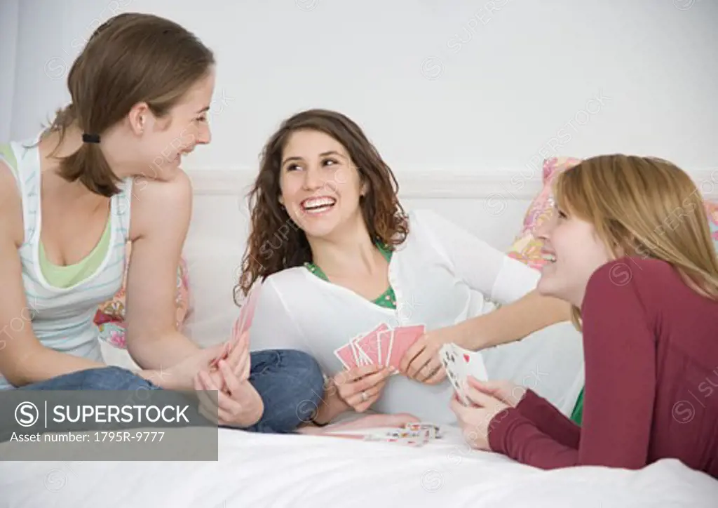Teenage girls playing cards on bed