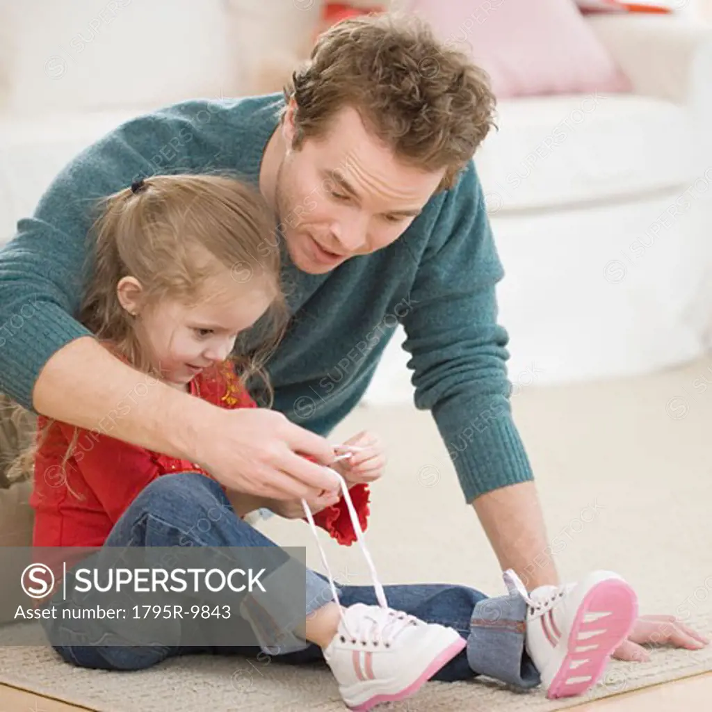 Father teaching daughter how to tie shoe