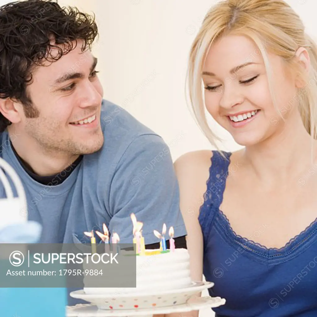 Man watching girlfriend smile at birthday cake