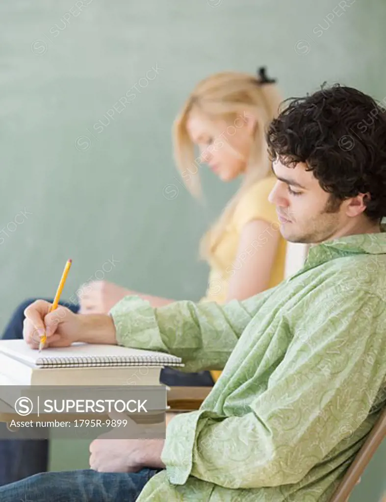 Man writing at desk in classroom