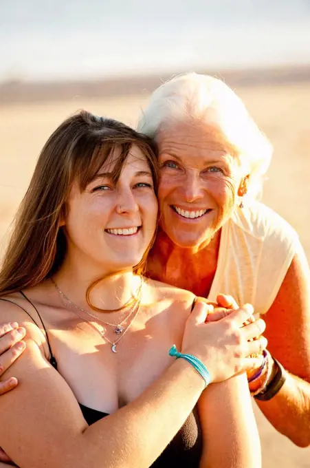 Portrait of mother and adult daughter smiling on beach