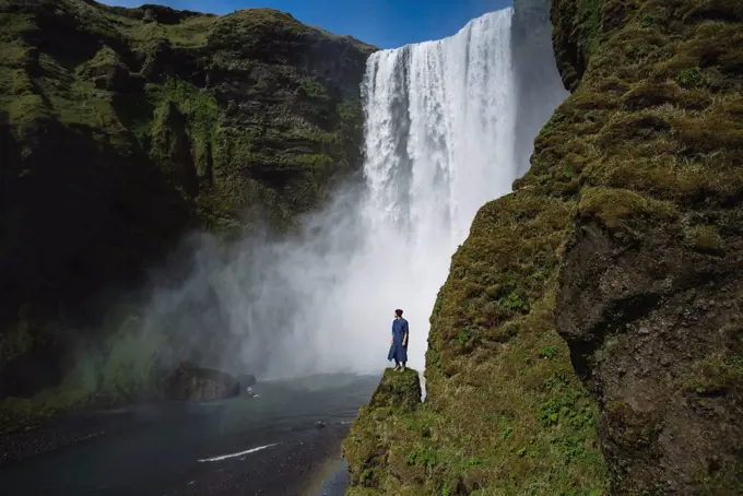 Man standing by Skogafoss waterfall in Iceland