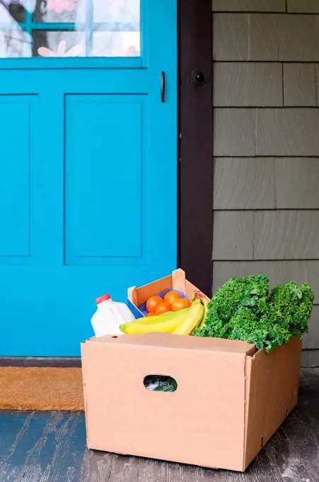 Box of delivered produce on house porch