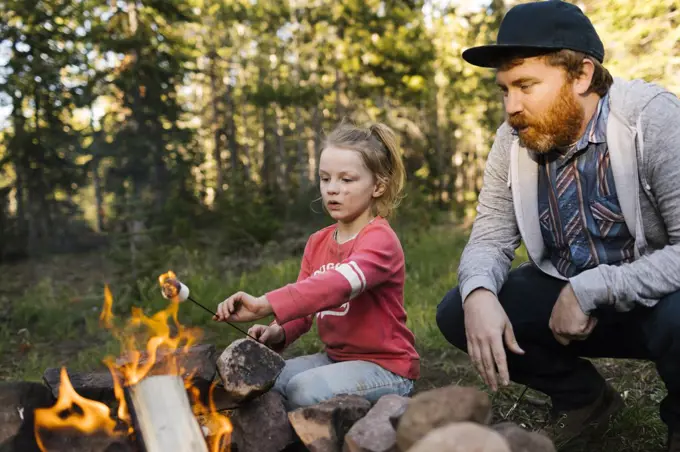 Man with daughter (6-7) roasting marshmallow above campfire, Wasatch Cache National Forest