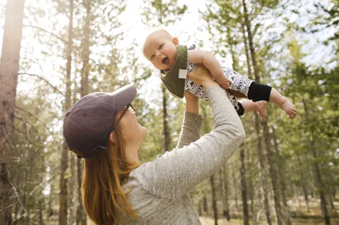 Woman holding baby son (6-11 months) in forest, Wasatch Cache National Forest