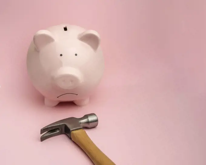 Piggy bank and hammer on pink background