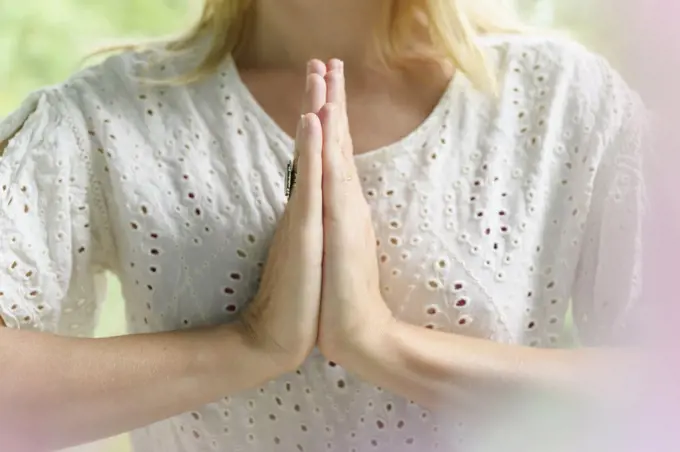 Close-up of blond woman doing yoga with hands clasped