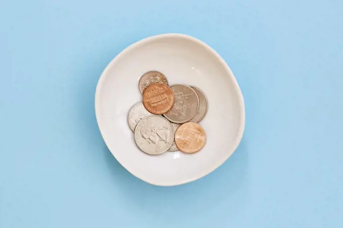 Coins in bowl on blue background