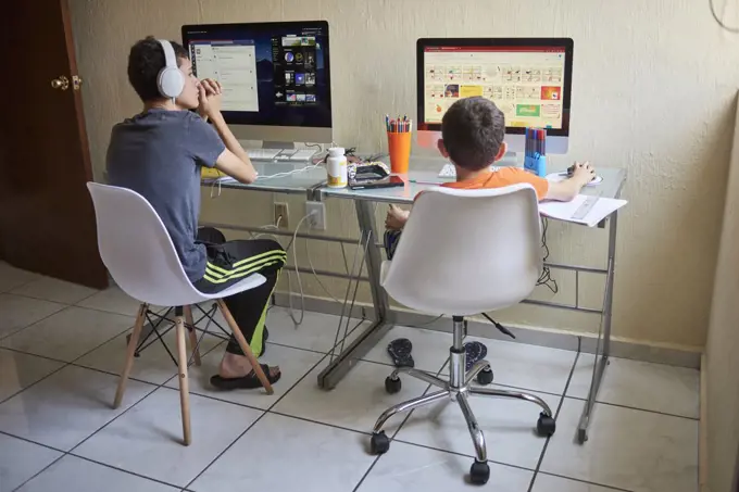 Two boys (8-9, 14-15) e-learning at home during Covid-19 lockdown