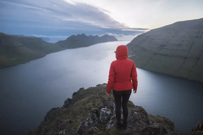 Denmark, Faroe Islands, Klaksvik, Woman standing on top of Klakkur mountain over sea and looking at view