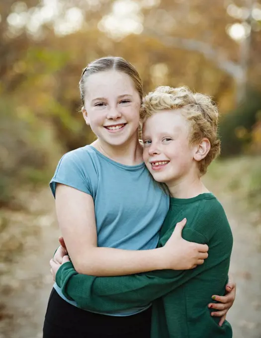 United States, California, Mission Viejo, Portrait of smiling brother (10-11) and sister (12-13) embracing in forest