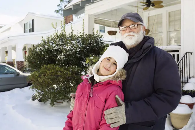 Grandfather and granddaughter outside house in winter