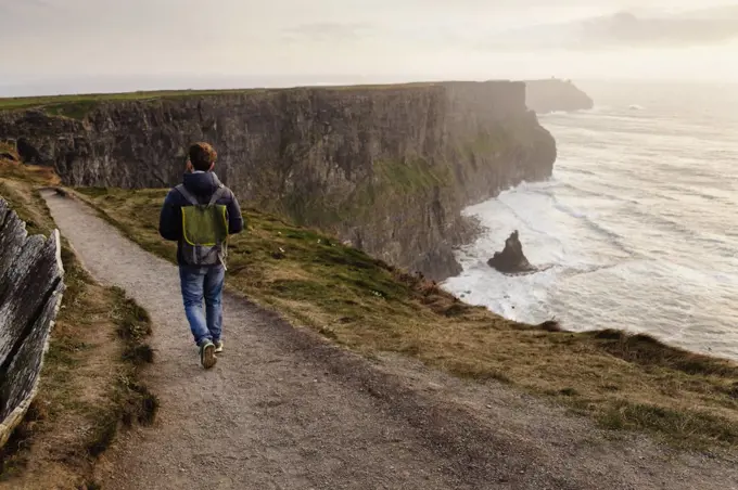 Mid adult man walking on The Cliffs of Moher, The Burren, County Clare, Ireland