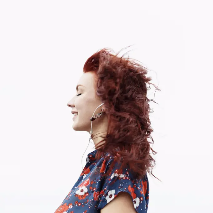 Profile of young woman with long red hair, wearing earphones