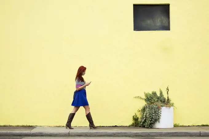 Young woman with red hair, walking along street