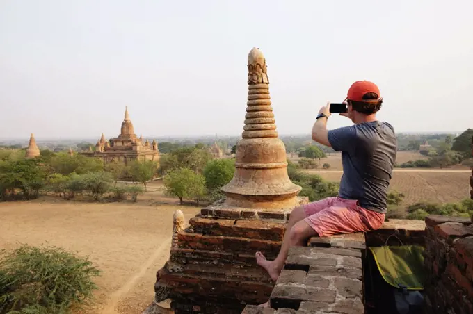 Man taking photograph from stone wall, Bagan Archaeological Zone, Buddhist temples, Mandalay, Myanmar