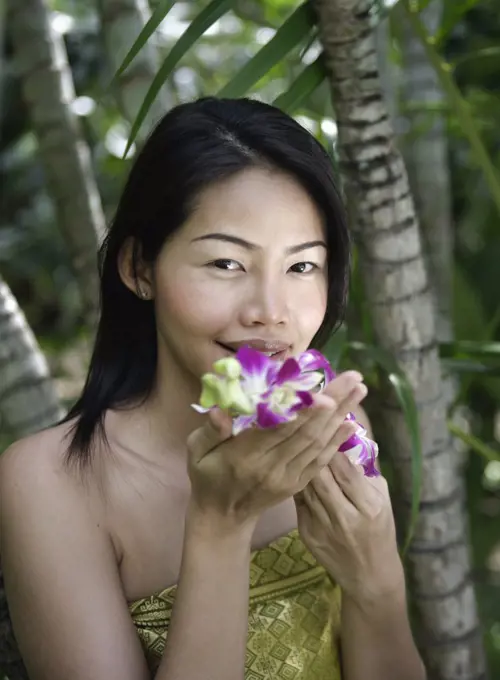Thailand, Koh Samui Island, Portrait of smiling woman smelling orchids