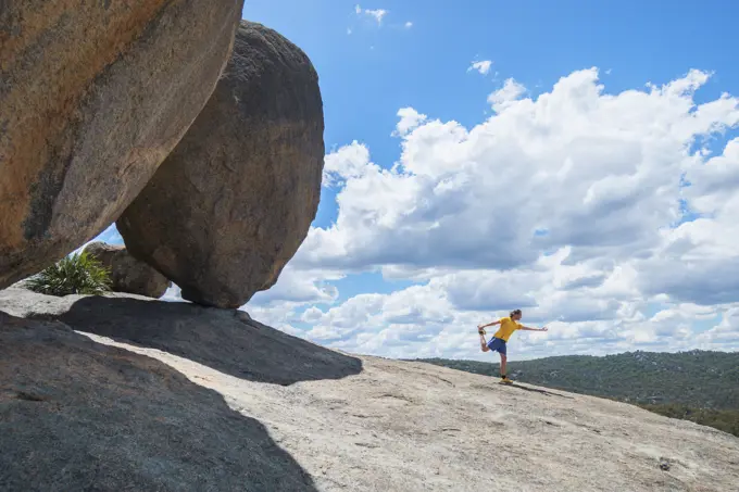 Australia, Queensland, Girraween National Park, Man exercising next to large boulder