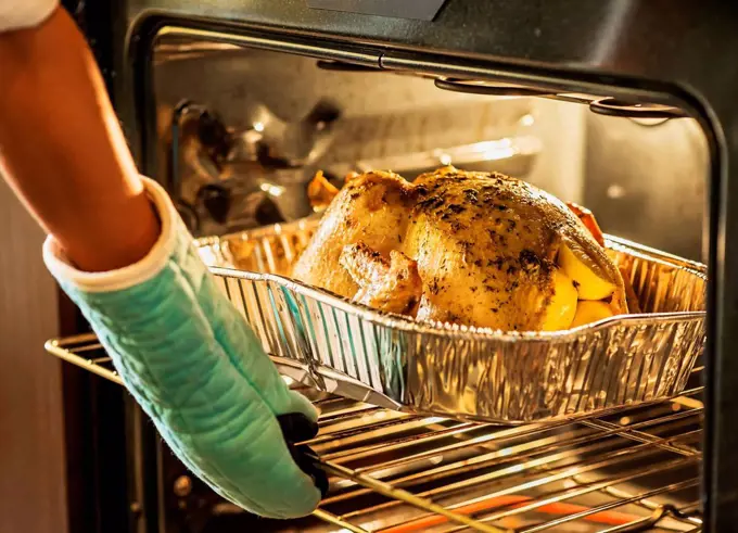 Woman checking turkey in oven