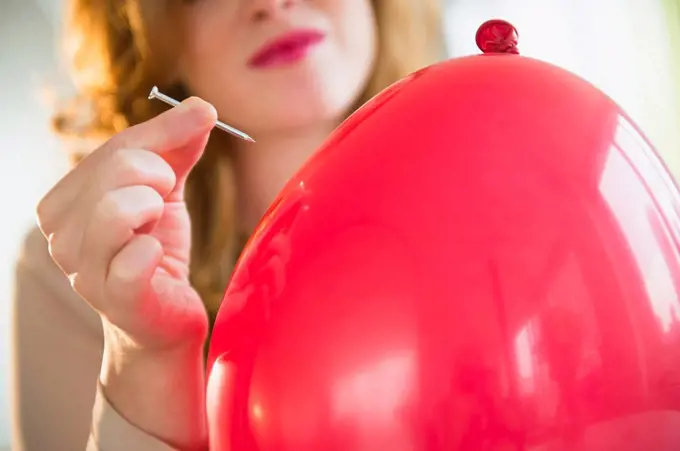 Young woman popping balloon