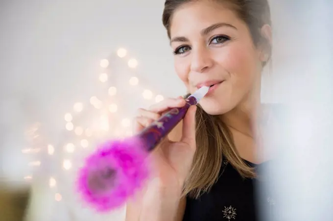 Young woman blowing noisemaker at party