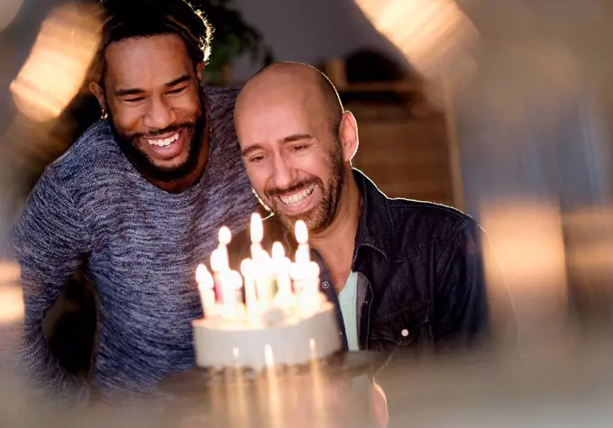 Smiley homosexual couple looking at birthday cake