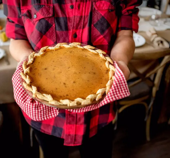 Woman holding baked pumpkin pie for Thanksgiving