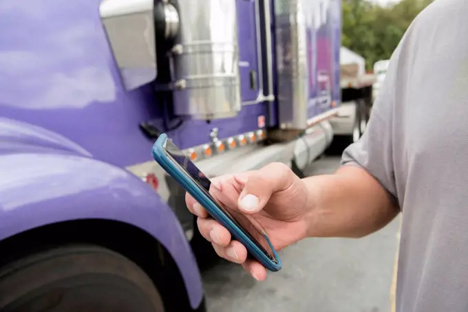 Hand of truck driver using smart phone