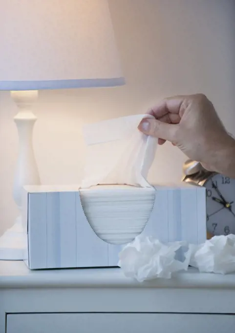 Hand pulling tissue out of box