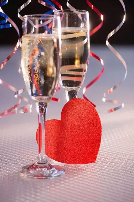Flutes with champagne and red paper heart, close_up
