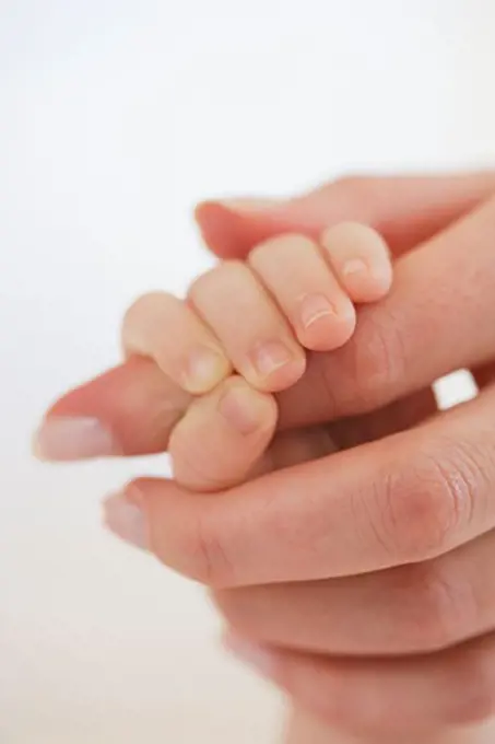 Close-up of baby holding mother's hand