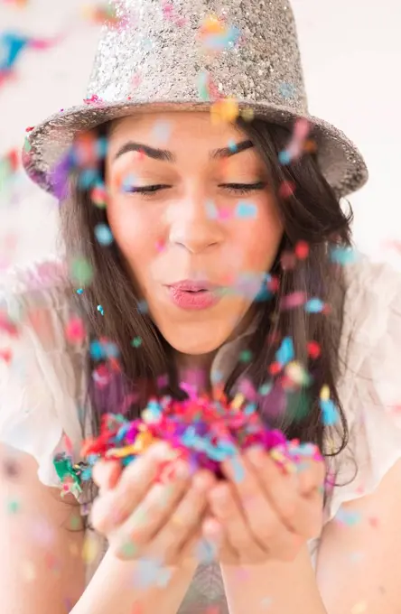 Portrait of young woman blowing confetti