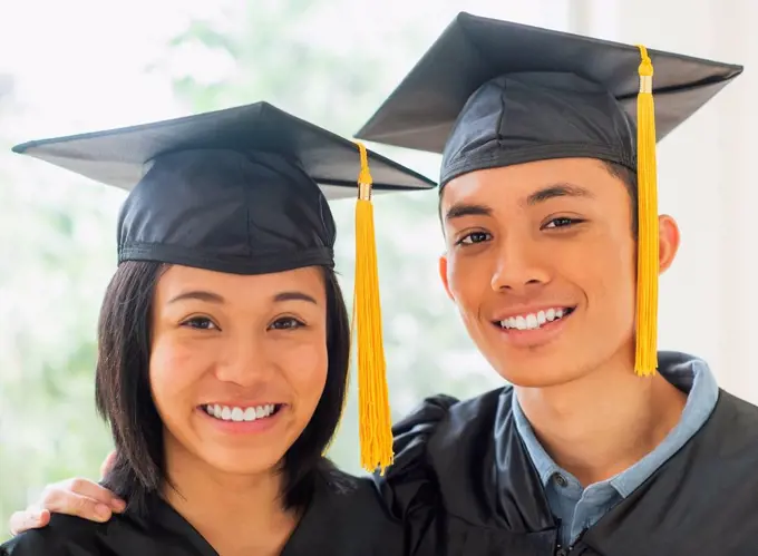 Portrait of young woman and young man wearing graduation gown