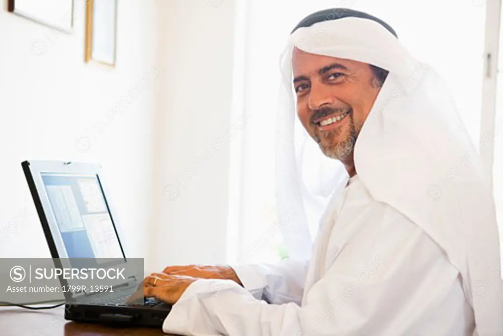 Man in office with laptop smiling (high key/selective focus)